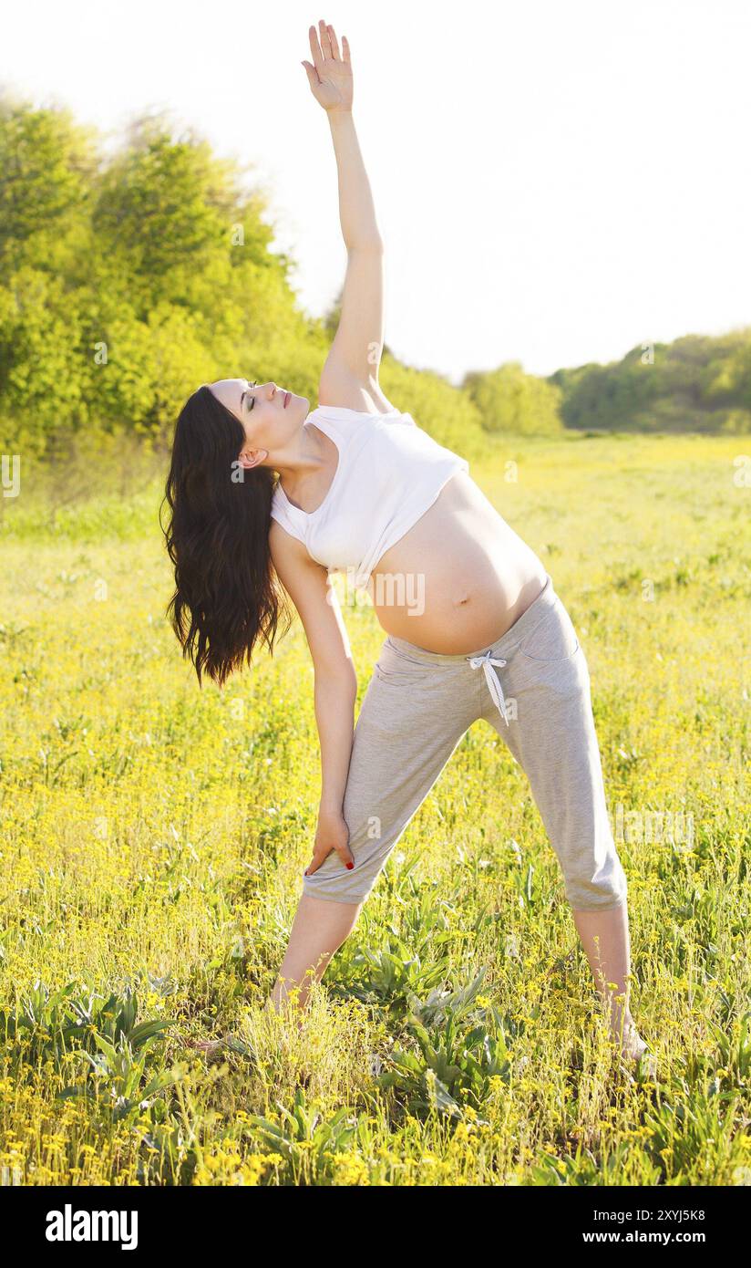 Un sano donna incinta fare yoga nella natura all'aperto Foto Stock