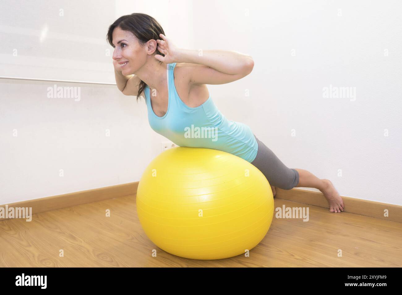 Donna che si allena con la palla in palestra. Donna Pilates che fa esercizi nella palestra con palla fitness Foto Stock