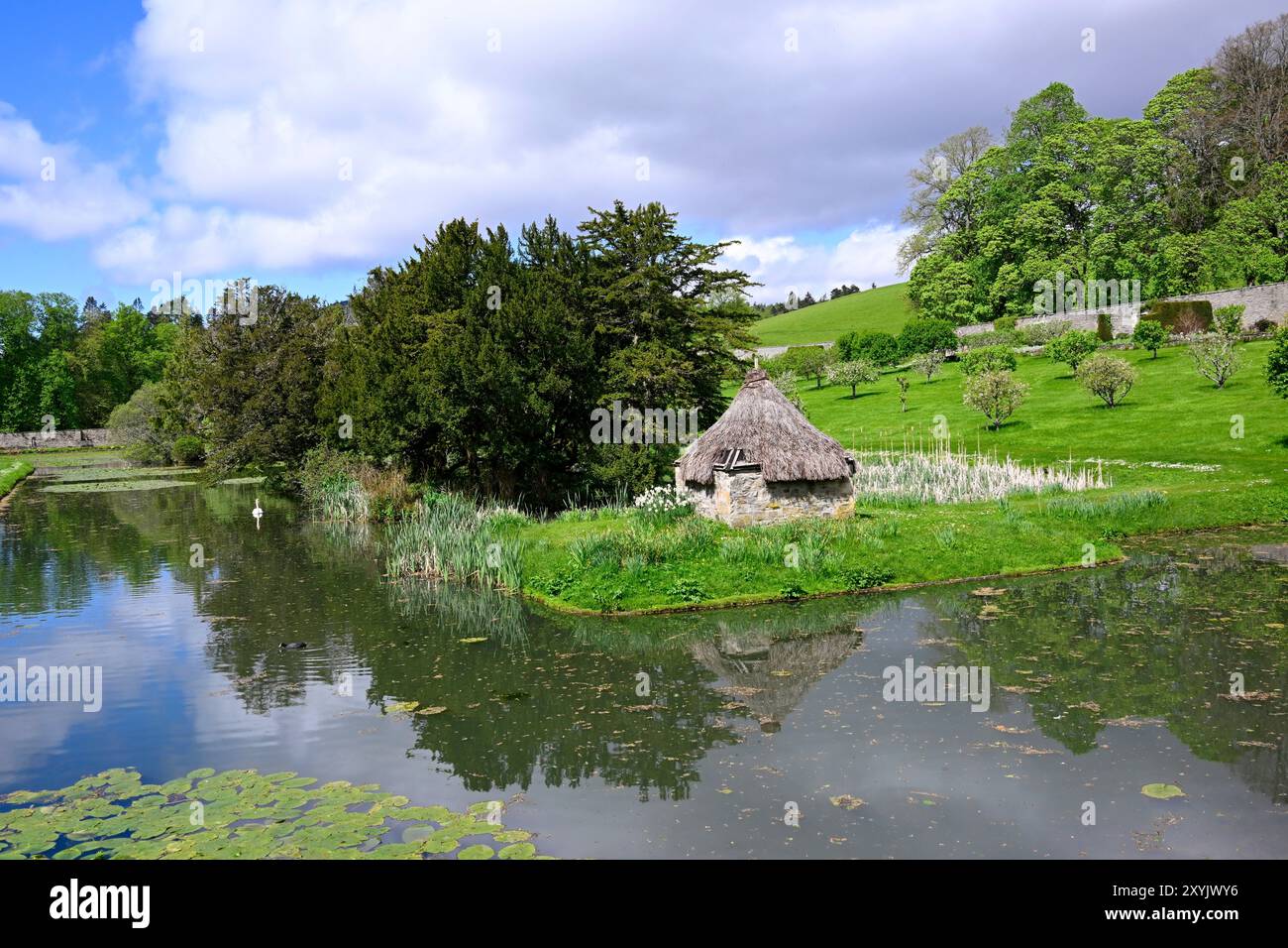Vista del lago, del cigno che nuota e della Casa dell'anatra sul tetto in paglia nel Giardino di Hercules, che è il Giardino murato di 9 acri al Castello di Blair Atholl Foto Stock