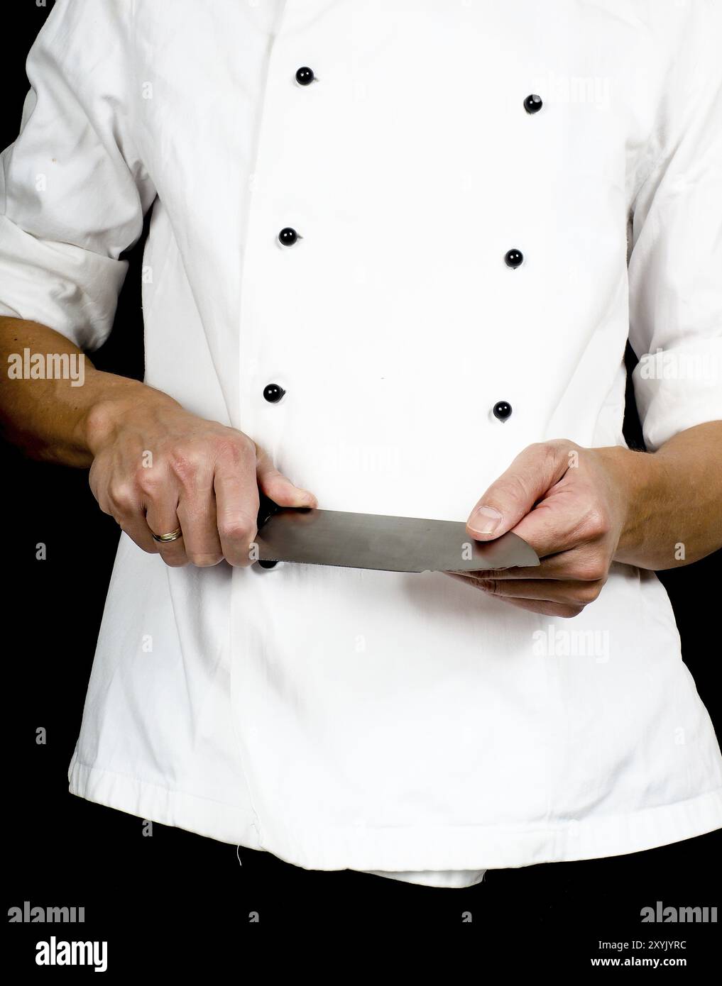 Chef professionale tenendo un affilato coltello da cucina in mani che indossa una giacca di cuochi Foto Stock