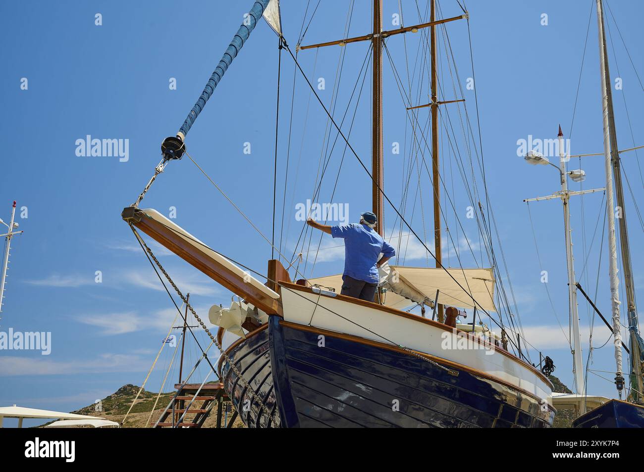 Un uomo ripara la barca a vela in legno all'albero sotto un cielo blu, Patmos Marine, cantiere navale, Diakofti, Patmos, Dodecaneso, Isole greche, Grecia, Euro Foto Stock