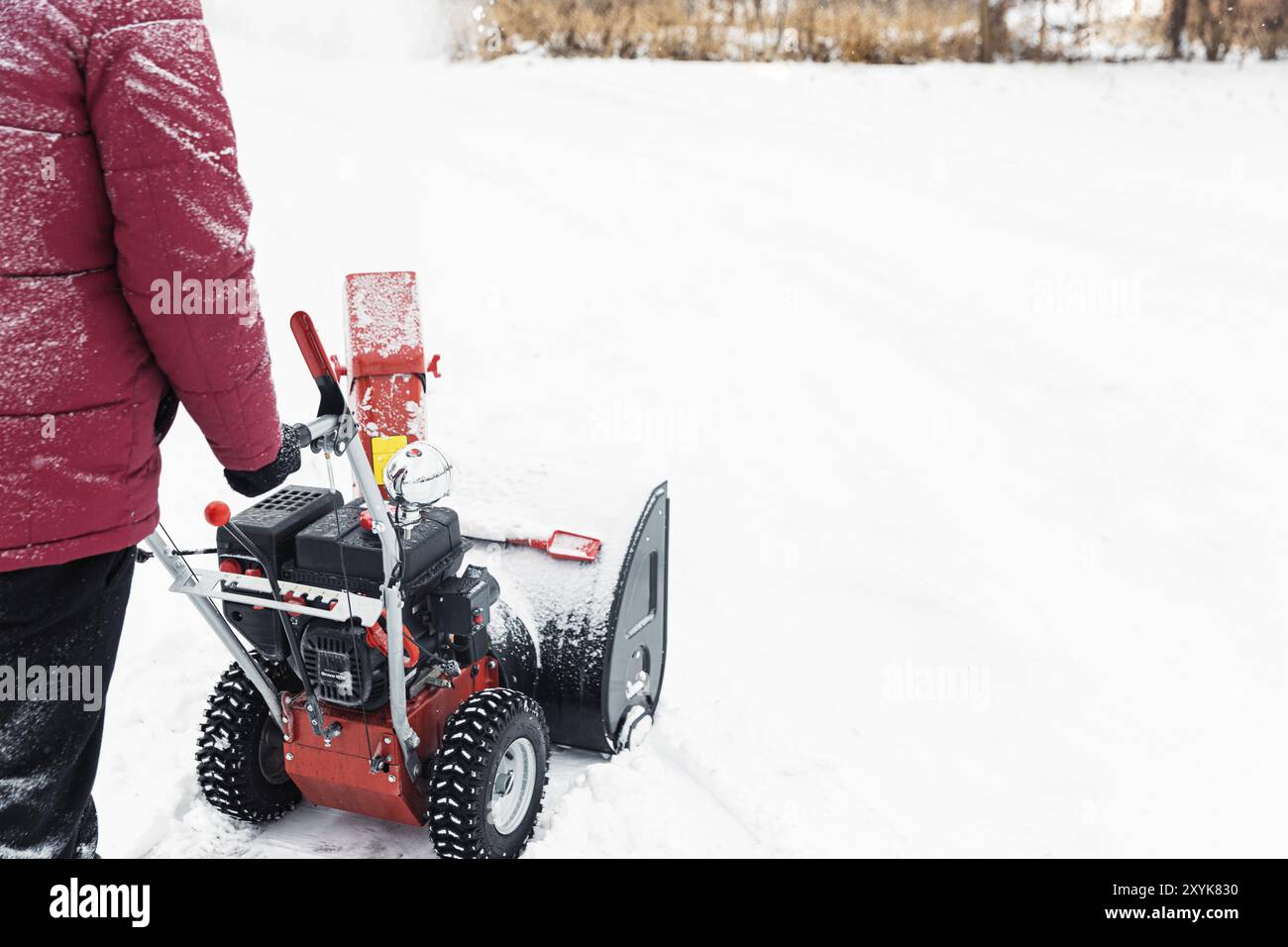 Particolare della soffiatrice portatile di neve rossa alimentata a benzina in azione. Uomo all'aperto che usa una macchina spazzaneve dopo la tempesta di neve. Rimozione neve, lanciatore assestan Foto Stock