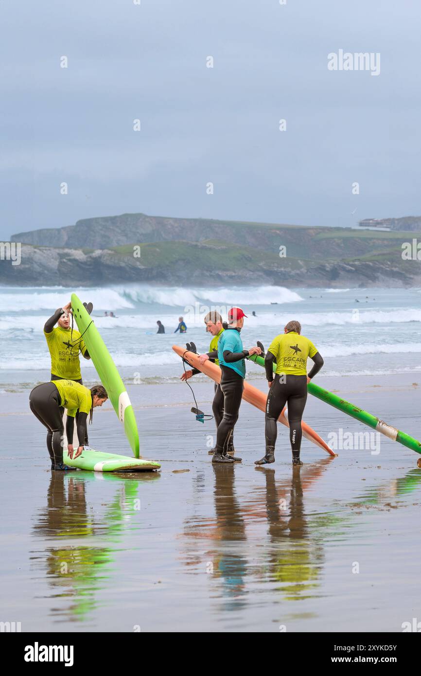 I principianti della Escape Surf School terminano una lezione con il loro insegnante di surf sulla spiaggia di Towan a Newquay in Cornovaglia nel Regno Unito. Foto Stock
