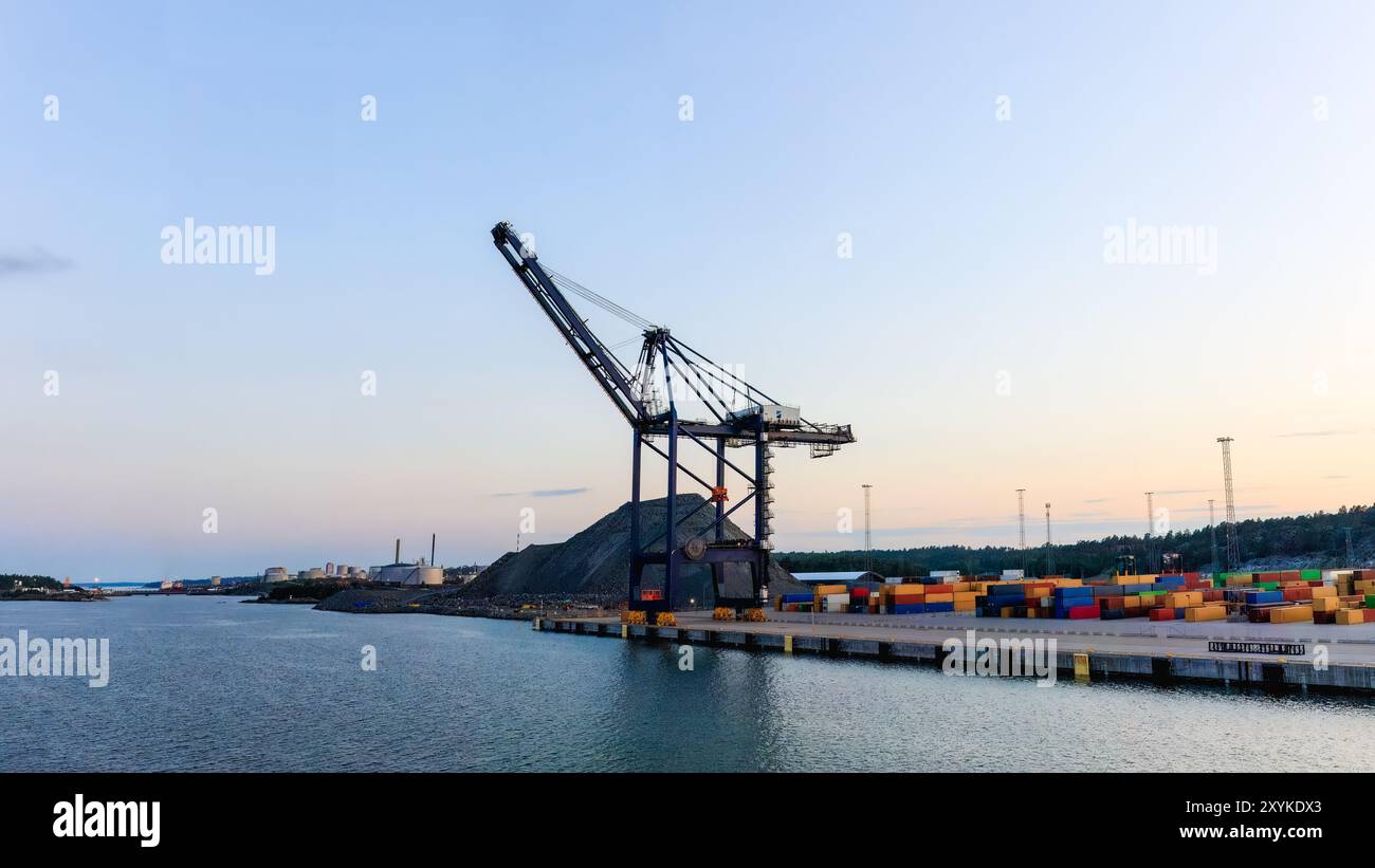 Gru per container in un porto al tramonto. Immagine ideale per temi relativi al commercio globale, alle operazioni industriali e alla logistica delle spedizioni. Copia spazio Foto Stock