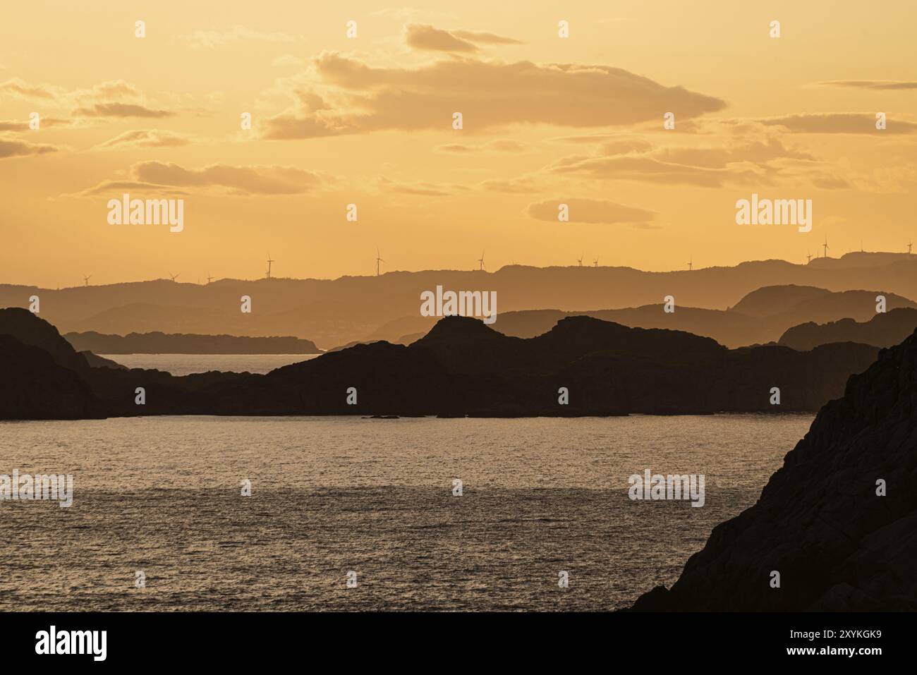 Tramonto d'oro su un arcipelago con turbine eoliche all'orizzonte Foto Stock