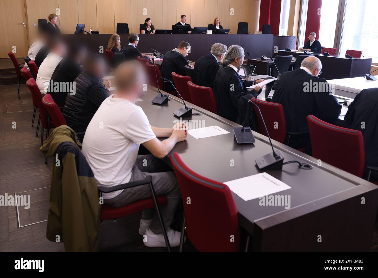 Duesseldorf, Germania. 30 agosto 2024. Diversi imputati (l) si siedono dietro i loro avvocati in tribunale presso il tribunale distrettuale durante il processo per un blocco stradale causato da una parata di nozze sull'autostrada A3. Un totale di sette imputati devono rispondere per gli eventi che hanno avuto luogo più di cinque anni fa. Credito: David Young/dpa - ATTENZIONE: Gli imputati sono stati pixelati per motivi legali/dpa/Alamy Live News Foto Stock