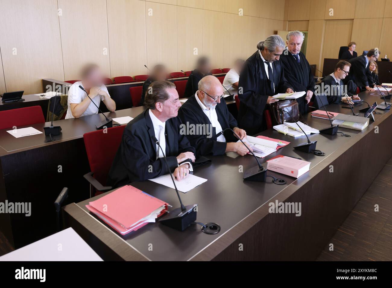 Duesseldorf, Germania. 30 agosto 2024. Diversi imputati (sul retro) siedono dietro i loro avvocati nell'aula del tribunale distrettuale durante il processo per un blocco stradale causato da una parata di nozze sull'autostrada A3. Un totale di sette imputati devono rispondere per gli eventi che hanno avuto luogo più di cinque anni fa. Credito: David Young/dpa - ATTENZIONE: Gli imputati sono stati pixelati per motivi legali/dpa/Alamy Live News Foto Stock