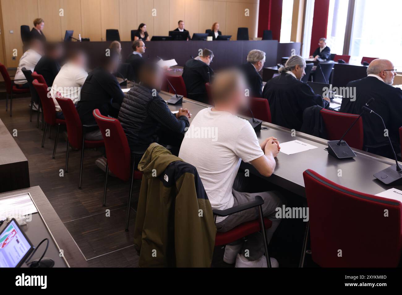 Duesseldorf, Germania. 30 agosto 2024. Diversi imputati (l) si siedono dietro i loro avvocati in tribunale presso il tribunale distrettuale durante il processo per un blocco stradale causato da una parata di nozze sull'autostrada A3. Un totale di sette imputati devono rispondere per gli eventi che hanno avuto luogo più di cinque anni fa. Credito: David Young/dpa - ATTENZIONE: Gli imputati sono stati pixelati per motivi legali/dpa/Alamy Live News Foto Stock