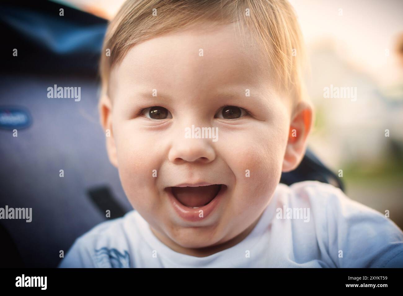 Un allegro bambino travolge di gioia, mostrando un sorriso contagioso mentre ama il calore di un pomeriggio soleggiato nel parco. Foto Stock