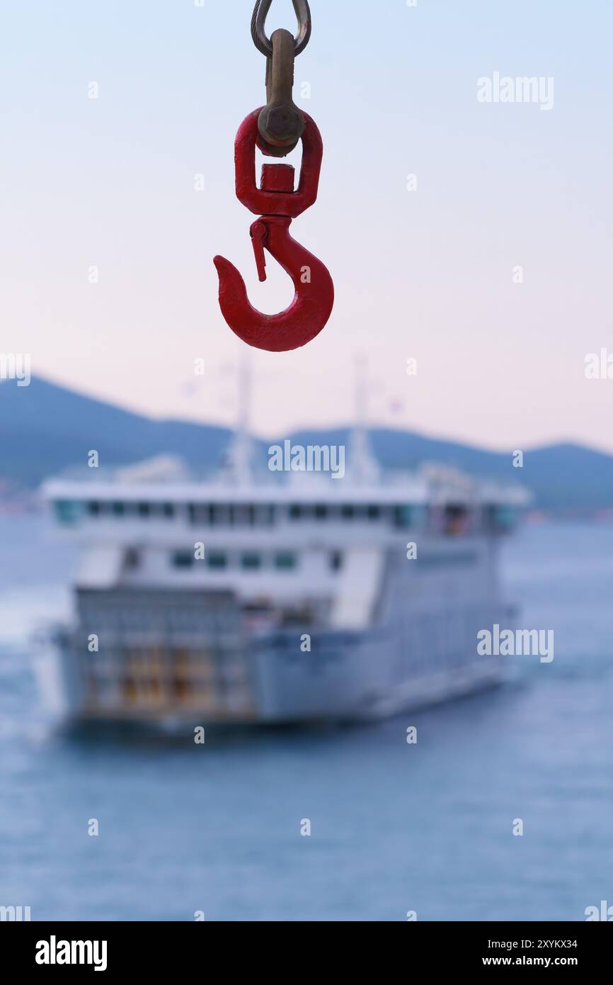 Primo piano del gancio della gru del traghetto e un traghetto visibile sullo sfondo. Concetti di viaggio, turismo, traffico marittimo e trasporto Foto Stock