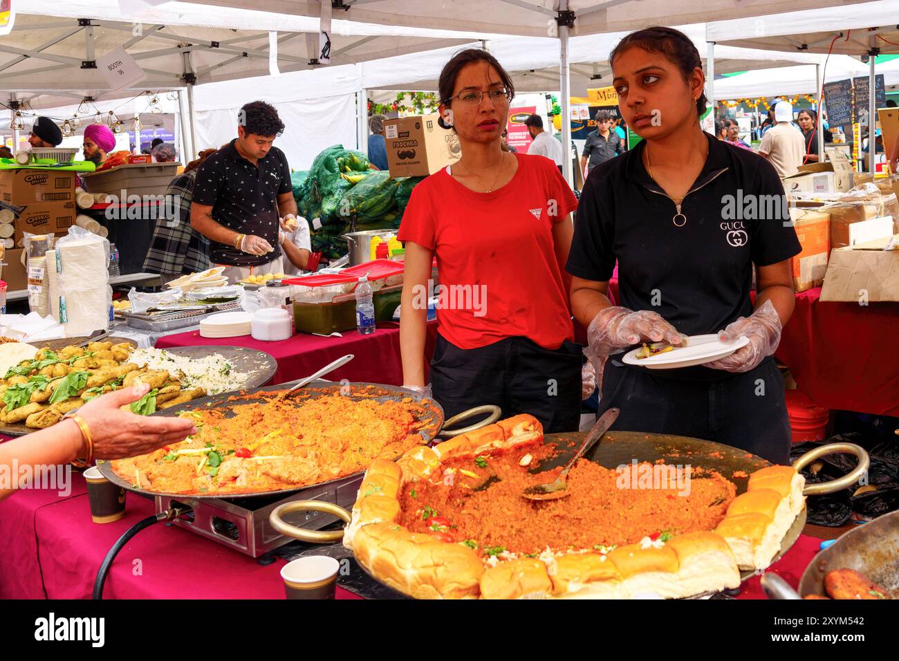 Due giovani donne che lavorano in un mercato che vende cibo durante il festival tradizionale Taste of India. Foto Stock