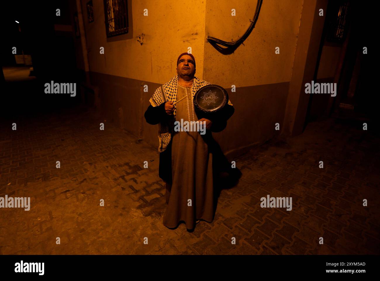 Khan Yunis, Striscia di Gaza, Palestina. 5 aprile 2022. Il palestinese Nizar al-Dabbas vagava per le strade di Khan Younis battendo un tamburo prima dell'alba durante il mese sacro musulmano del Ramadan. La figura del batterista musulmano o “Masaharati” fa parte di una vecchia tradizione con lo scopo di risvegliare i musulmani e ricordare loro il pasto suhoor che precede il digiuno Foto Stock