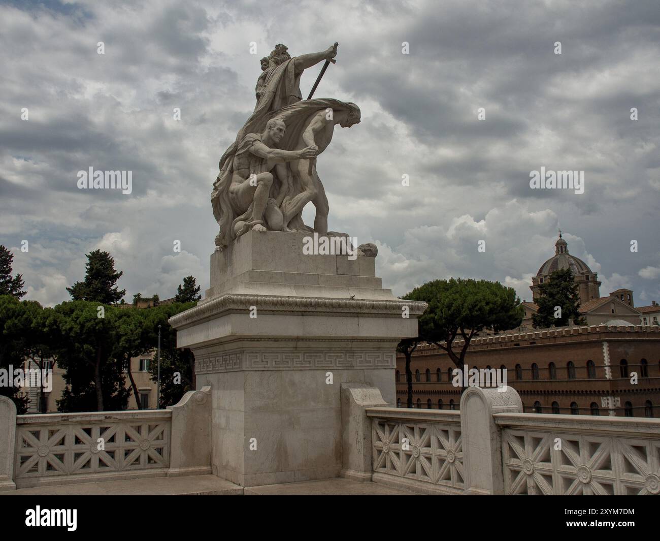 Un'imponente statua su un piedistallo decorato, incorniciata da alberi e un cielo nuvoloso, roma, italia Foto Stock