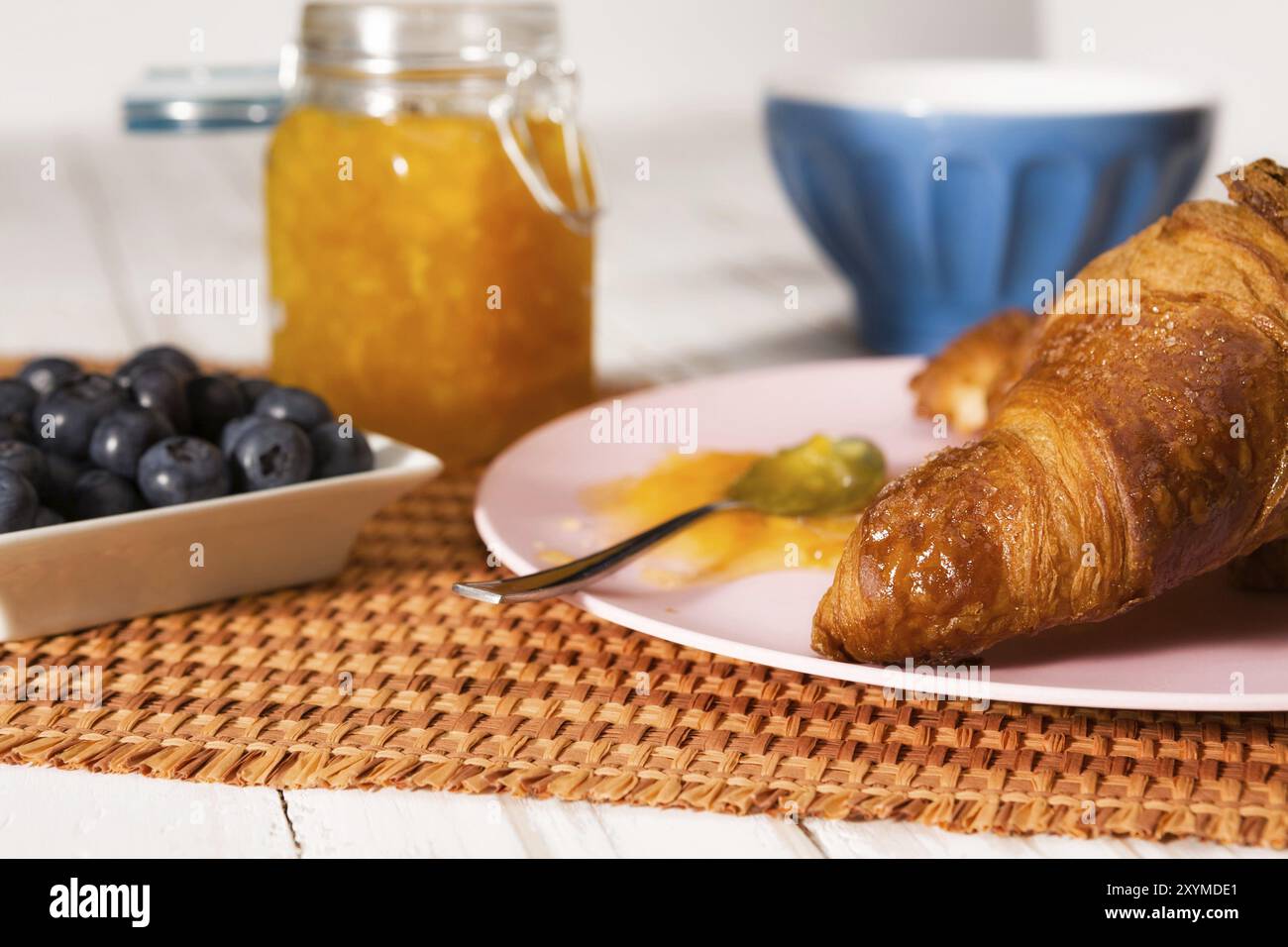 Vista dettagliata del cornetto, mirtilli, latte e marmellata di arancione su una tovaglia Foto Stock