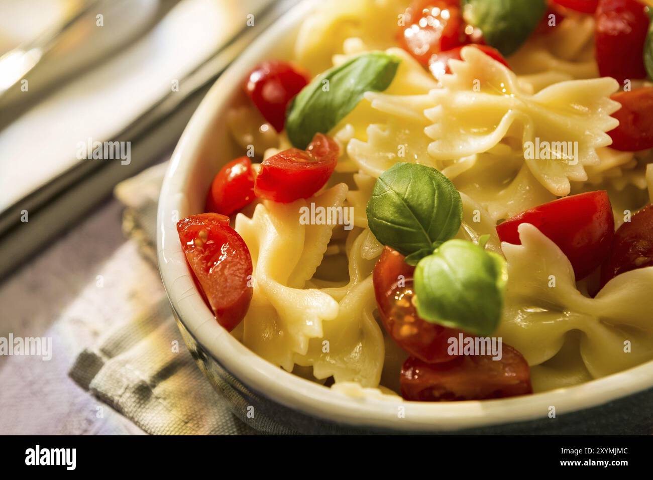 Primo piano di farfalle italiane con pomodori e basilico su uno sfondo colorato Foto Stock