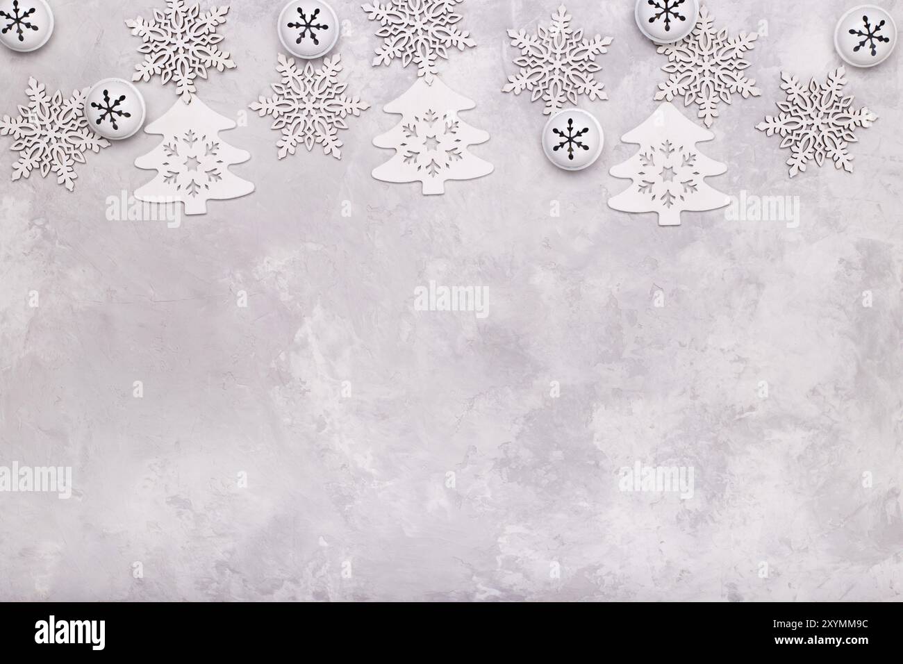 Modello natalizio piatto composto da fiocchi di neve campane e alberi su sfondo di pietra grigia. Concetto invernale Foto Stock