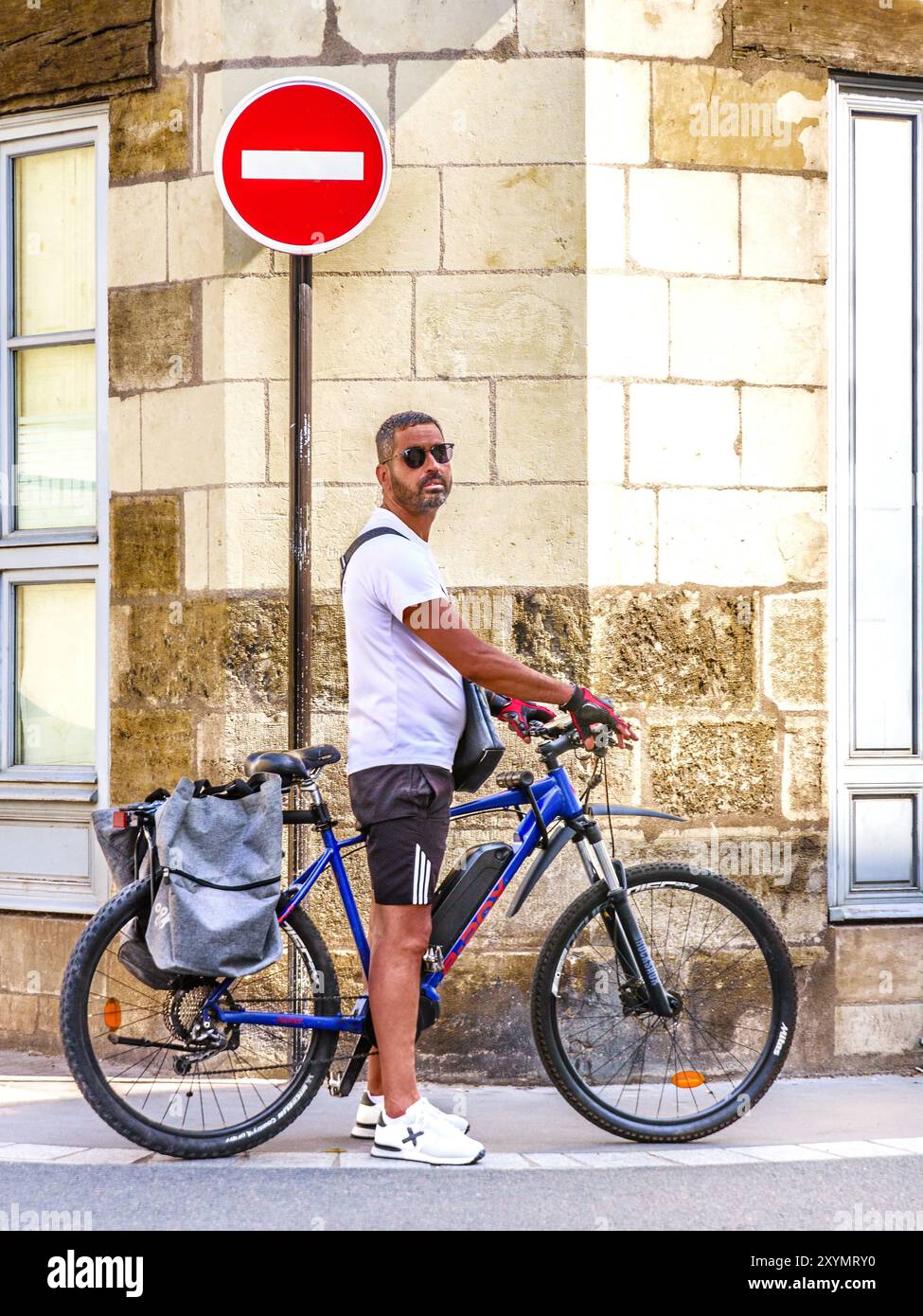 Uomo in bicicletta elettrica ibrida in attesa al cartello di ingresso nel centro città - Tours, Indre-et-Loire (37), Francia. Foto Stock