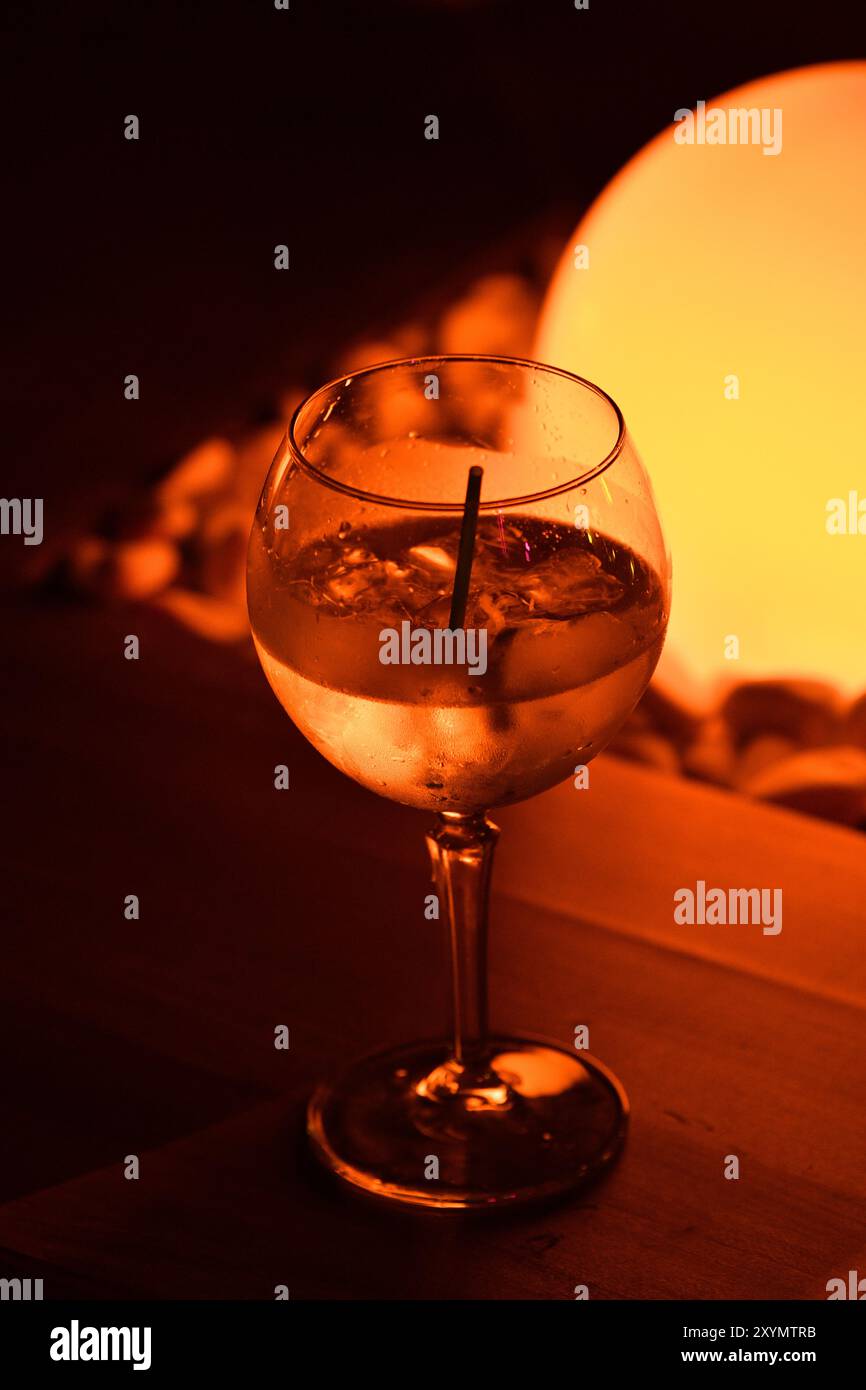 Vita notturna: Vetro illuminato con alcol e luce arancione. Foto Stock