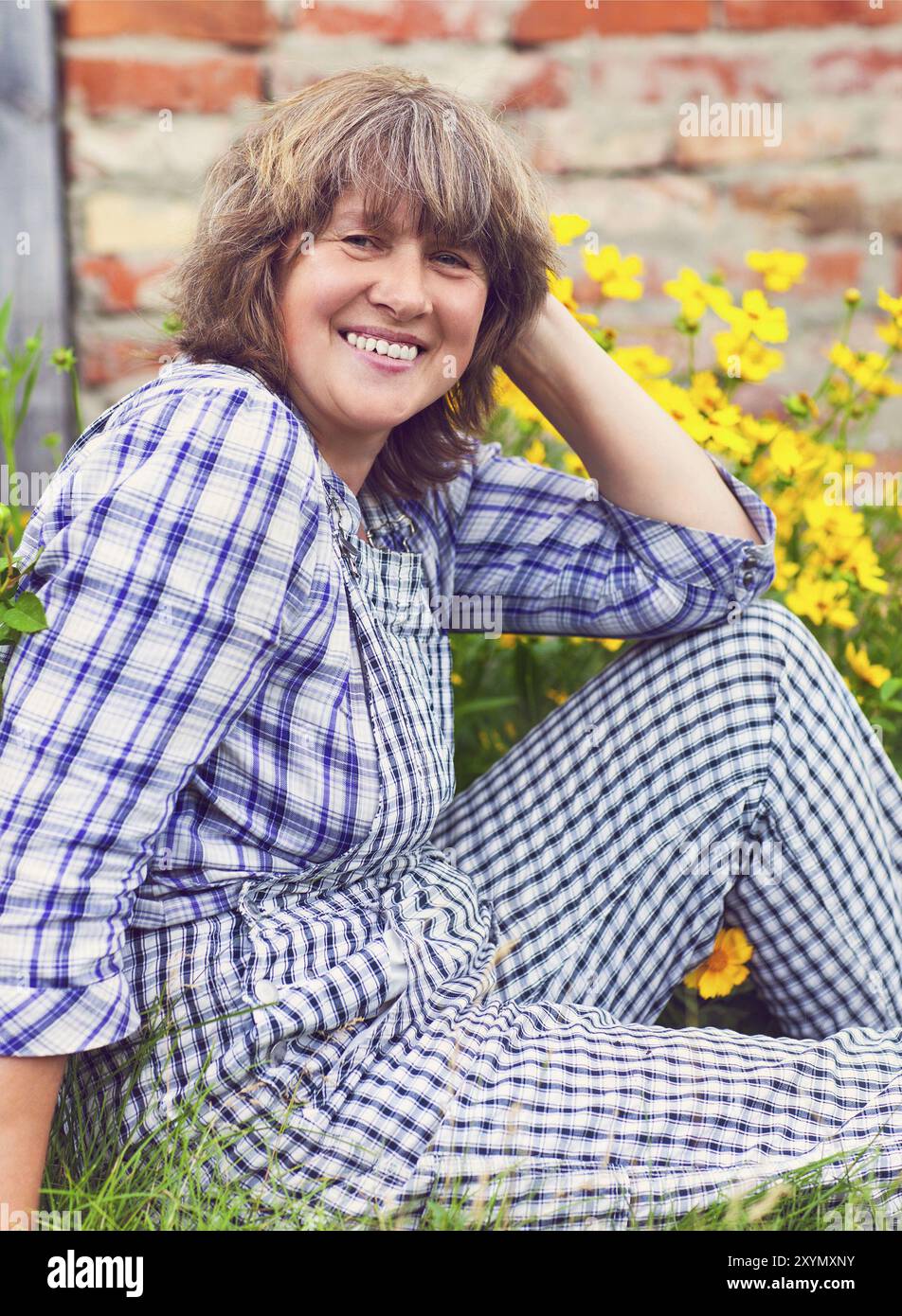 La mezza età lavora una donna nel suo giardino Foto Stock