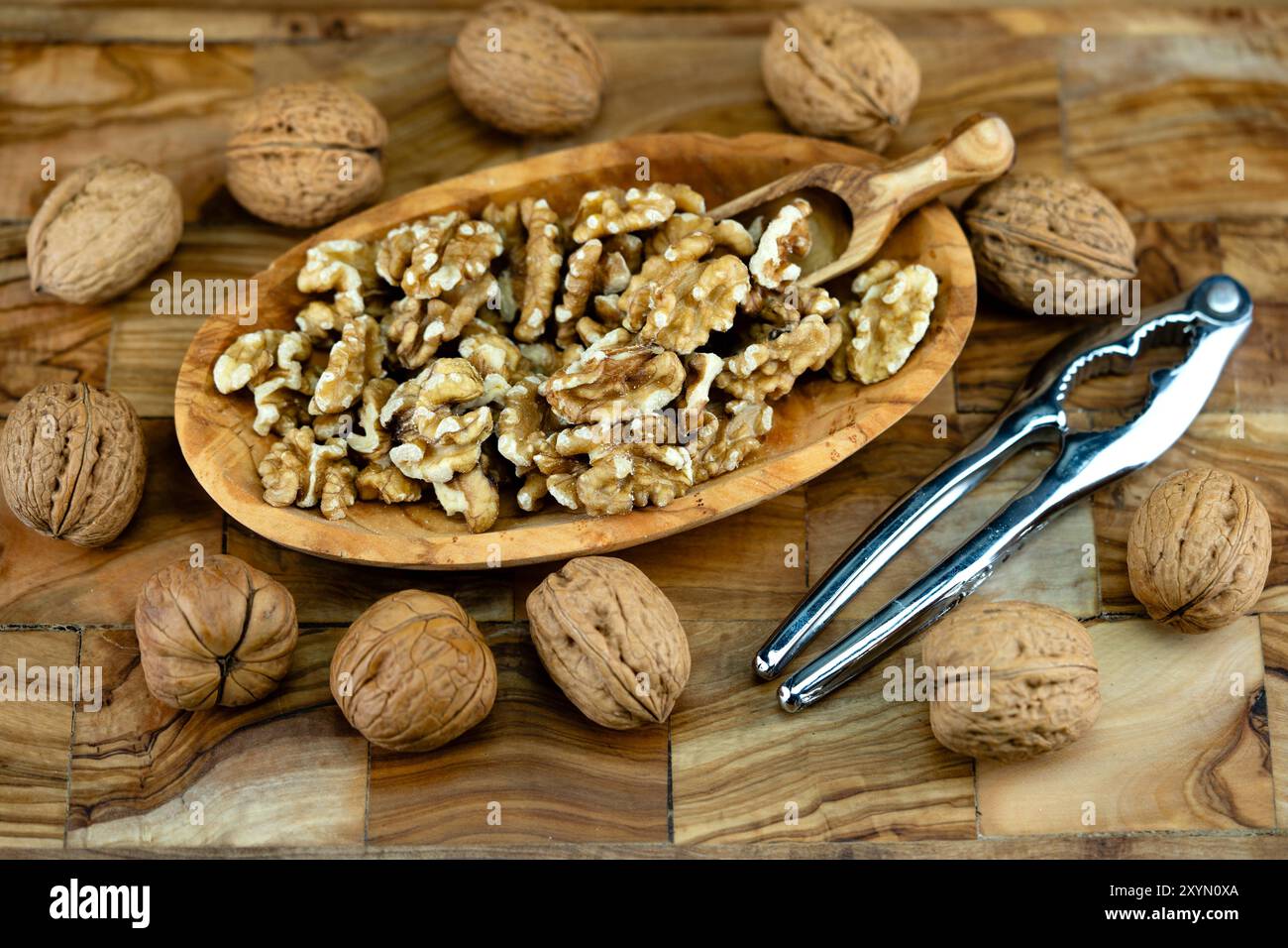 noce (Juglans regia), noci incrinate su un piatto di legno con noci intere, paletta in legno e schiaccianoci Foto Stock