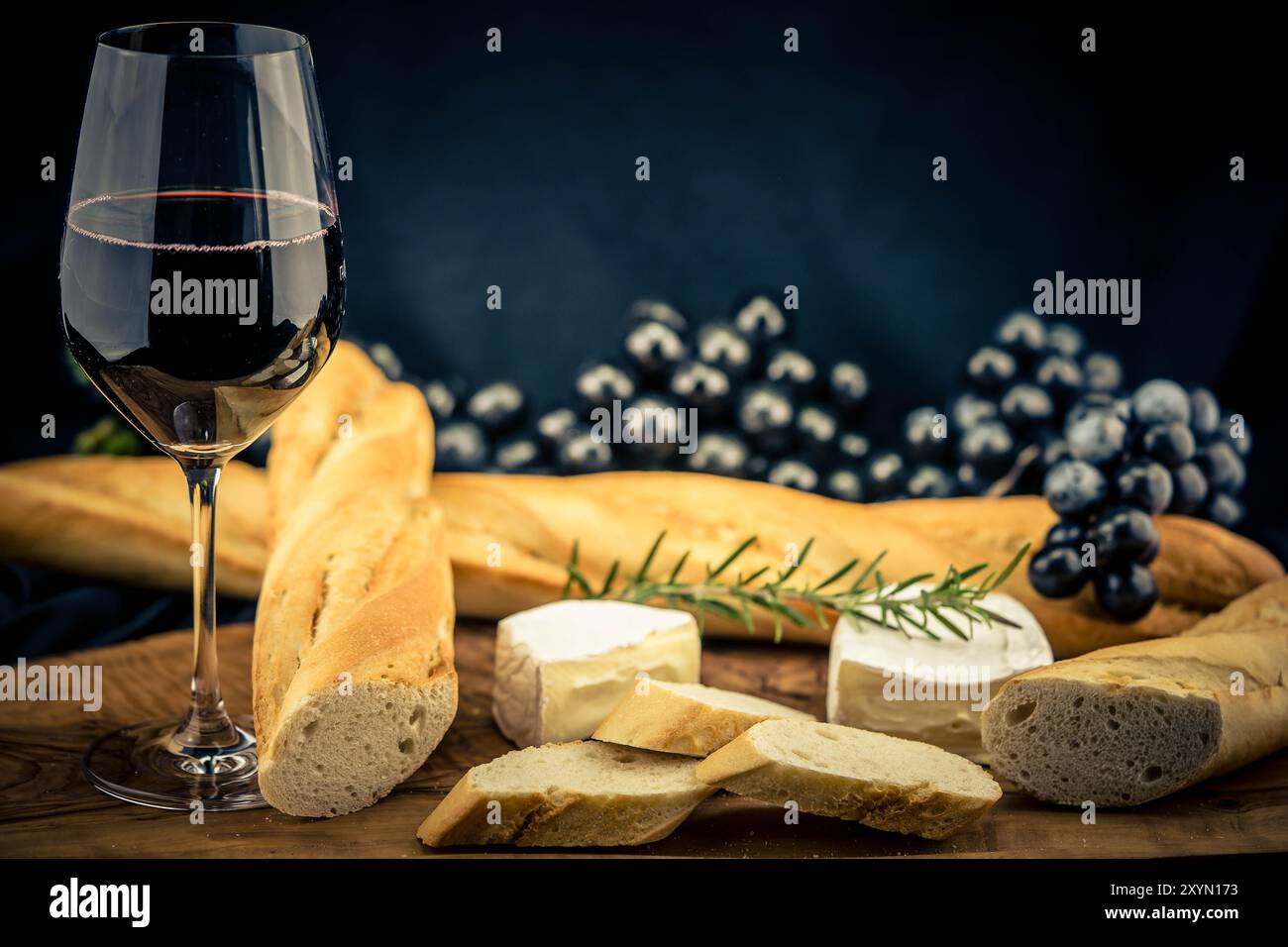 Bicchiere di vino rosso con uva, baguette e formaggio Foto Stock