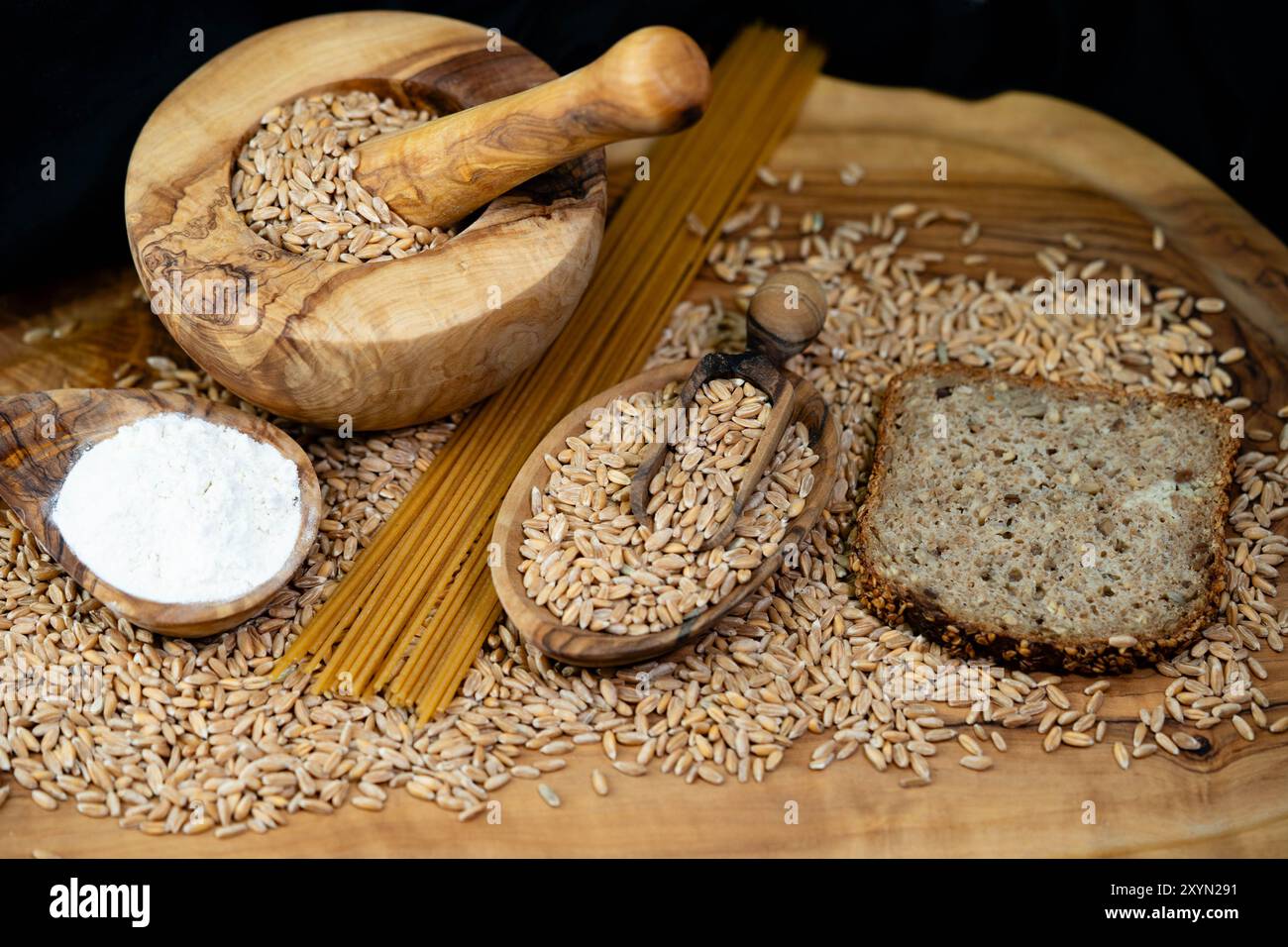 Grano farro (Triticum spelta), semi di farro, farina di farro e pane di farro con Malta, ciotola di legno e pala di legno Foto Stock
