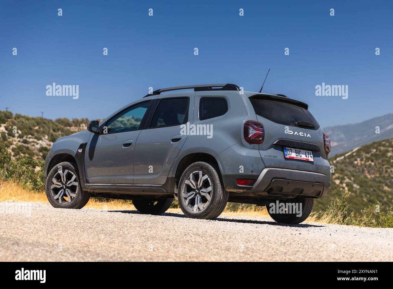 Kalkan, Turchia - 17 agosto 2024: Vista laterale posteriore 2024 Dacia Duster. Il moderno fuoristrada grigio si trova sul ciglio della strada vicino alla strada di montagna su una soleggiata Foto Stock