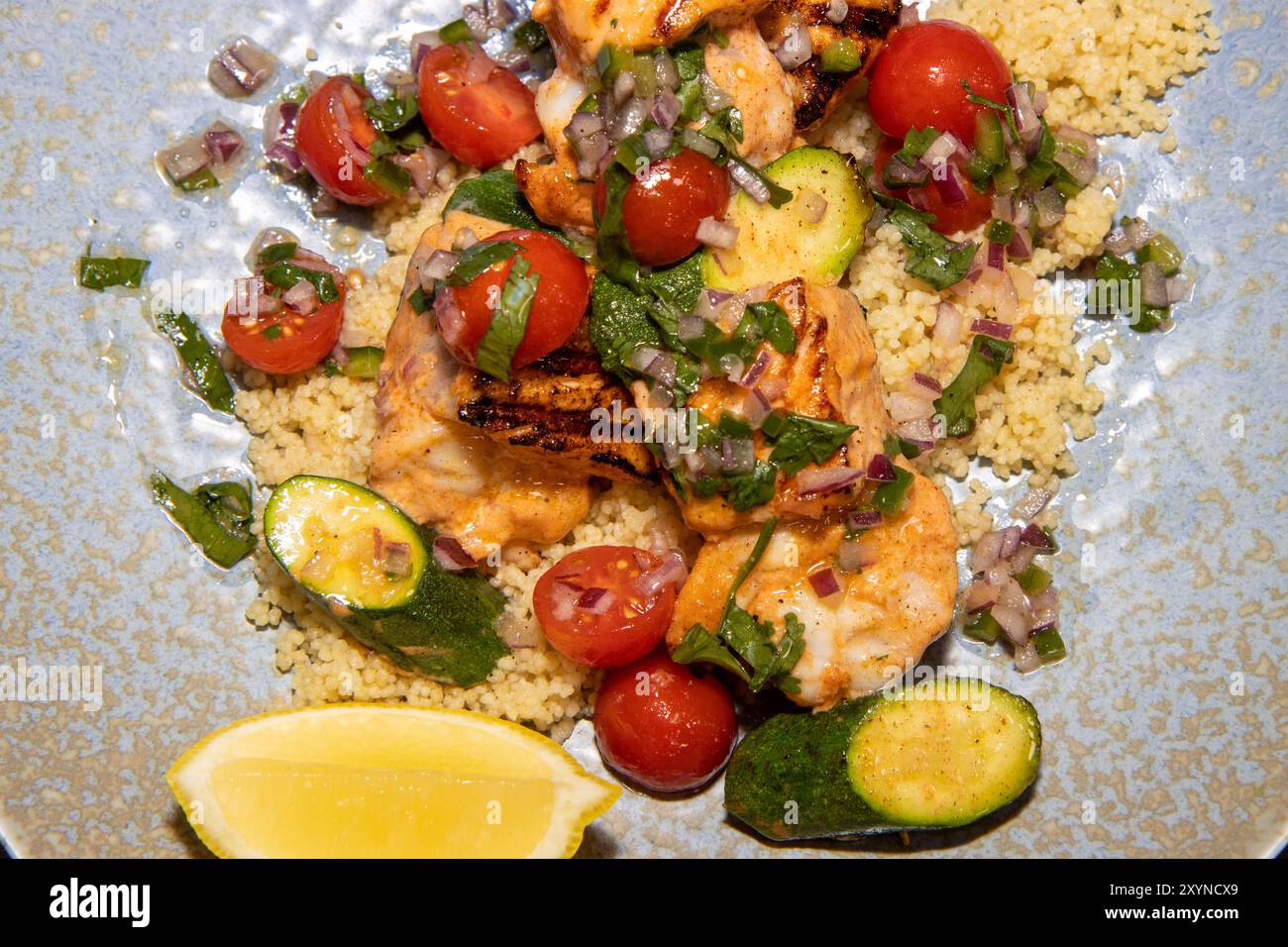 Un delizioso piatto di salmone di primavera e spiedini di gamberi con insalata couscous e salsa agli agrumi Foto Stock