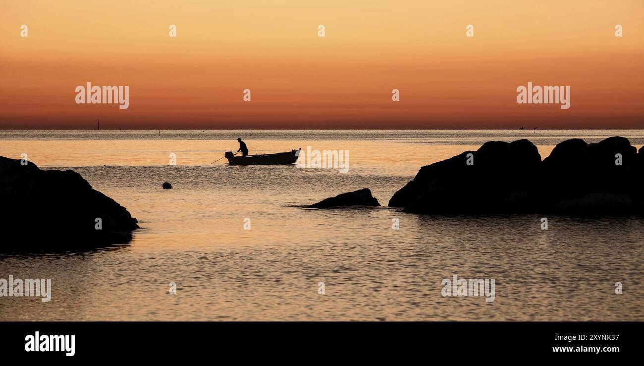 Pescatore nelle prime ore del mattino all'alba in attesa di tornare in barca alla propria rete Foto Stock