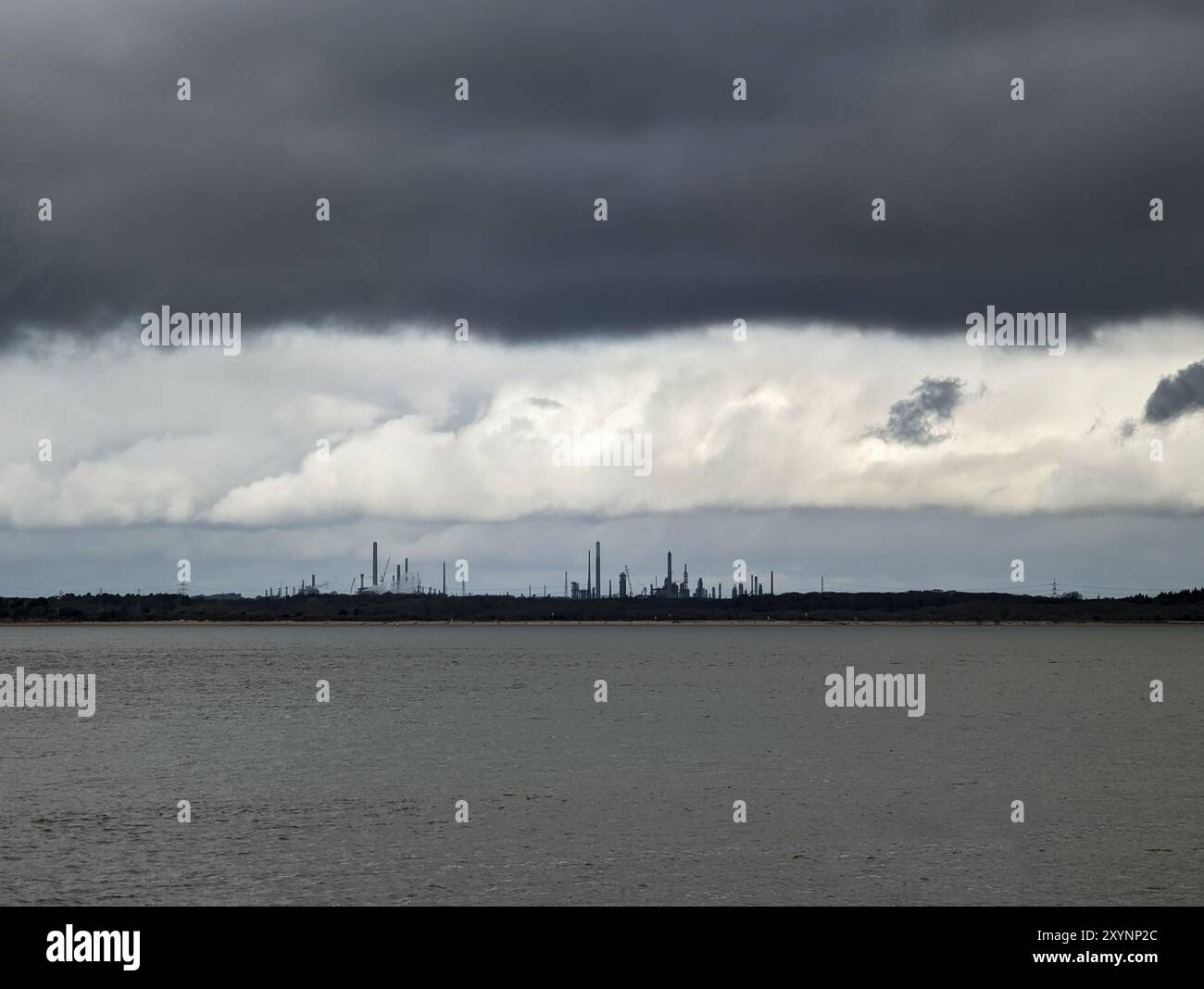 Le linee di strati di nuvole scure sono minacciose sopra lo stabilimento di raffineria petrolchimica di Fawley sulla costa di Solent Foto Stock