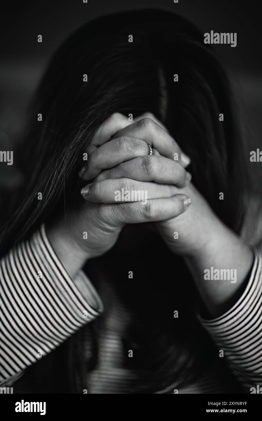 Primo piano Ritratto di una donna con le mani piegate davanti al viso che prega, concetto cristiano Foto Stock