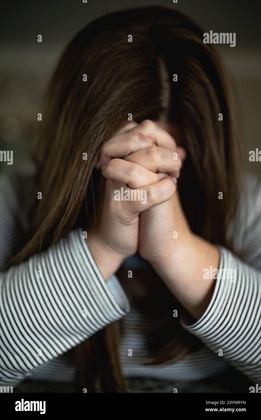 Primo piano Ritratto di una donna con le mani piegate davanti al viso che prega, concetto cristiano Foto Stock