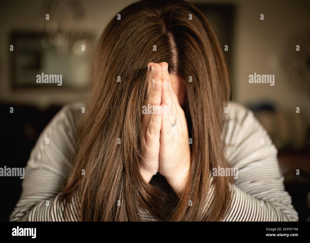 Primo piano Ritratto di una donna con le mani piegate davanti al viso che prega, concetto cristiano Foto Stock