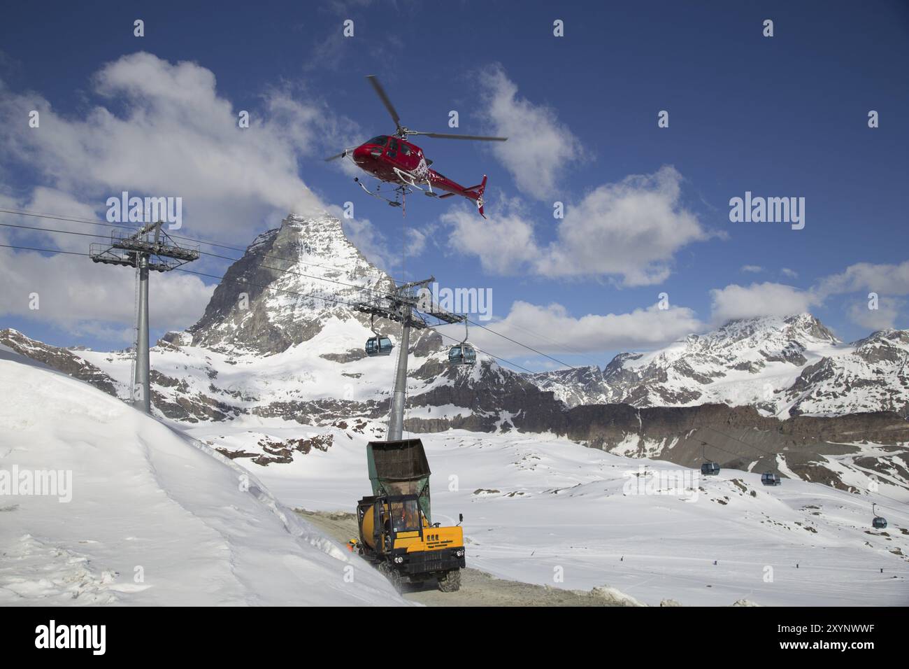 Zermatt, Svizzera, 13 aprile 2017: Un elicottero che carica cemento in un cantiere sulle montagne svizzere, in Europa Foto Stock