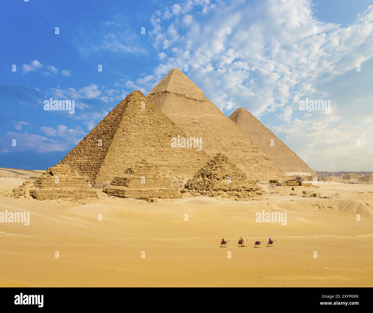 Tutte le piramidi egiziane sono raggiungibili a piedi con una fila di cammelli in primo piano a Giza, il Cairo, in Egitto. Ampio teleobiettivo per riprese con ampio spazio di copia Foto Stock