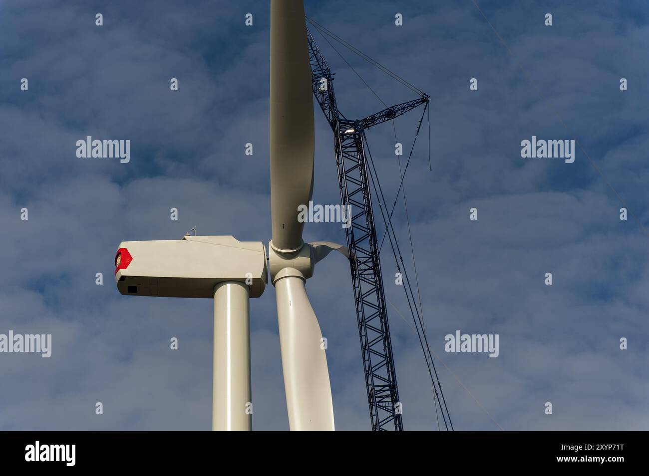 Fase finale del montaggio di un rotore sulla navicella del generatore di una turbina eolica Foto Stock