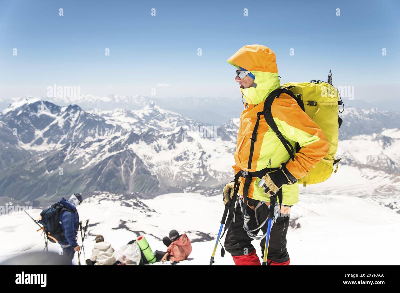 Un ritratto di un alpinista invecchiato in attrezzatura professionale per scalare le montagne sullo sfondo di altri scalatori e vette innevate del Cauca Foto Stock