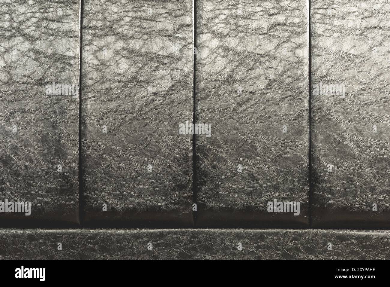 La consistenza della vera pelle sul retro del letto. Le strisce verticali della pelle sono nere. Costosa lucentezza della pelle artificiale Foto Stock