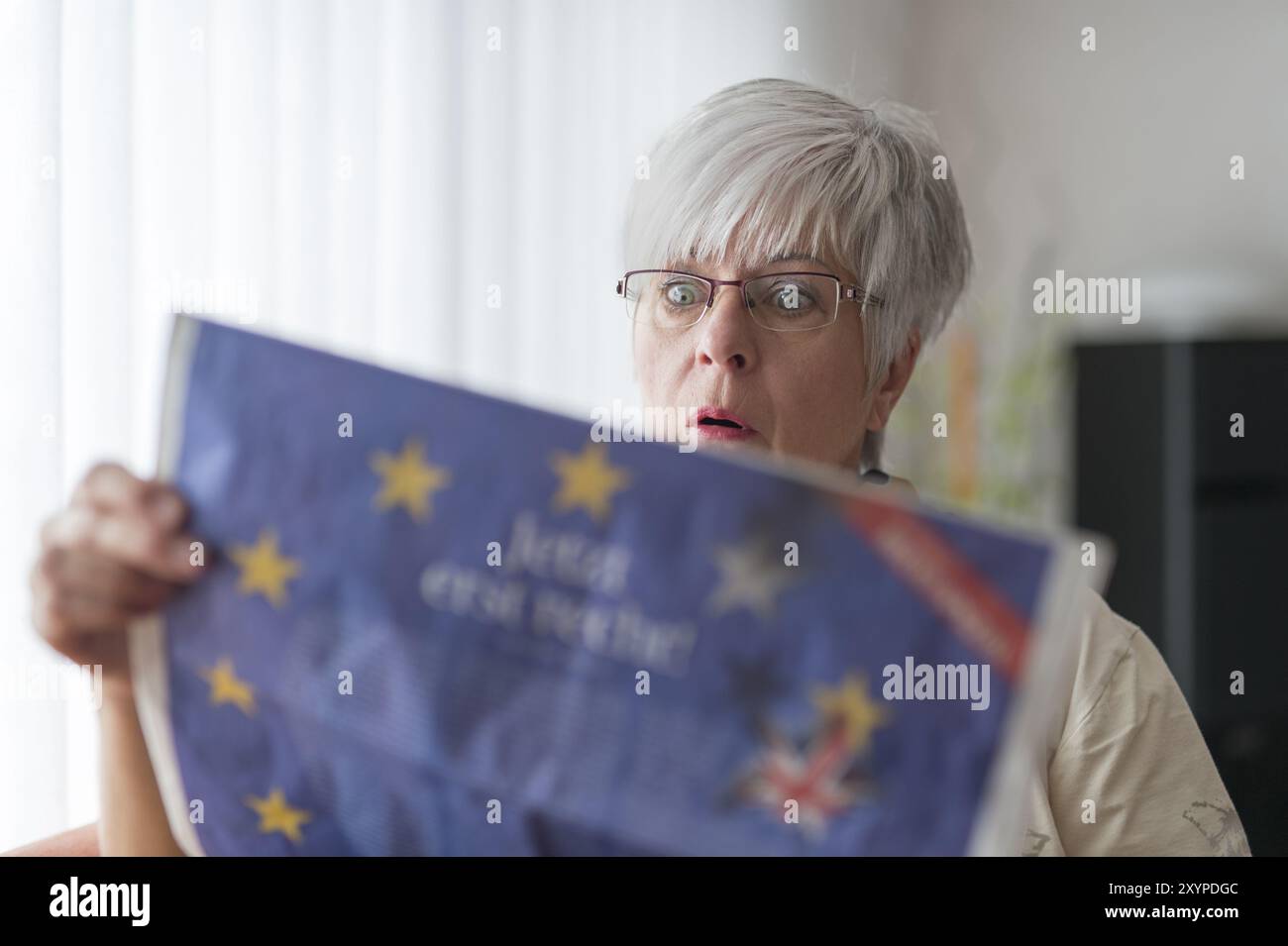 Una signora anziana legge le notizie sulla Brexit e apre gli occhi sotto shock Foto Stock