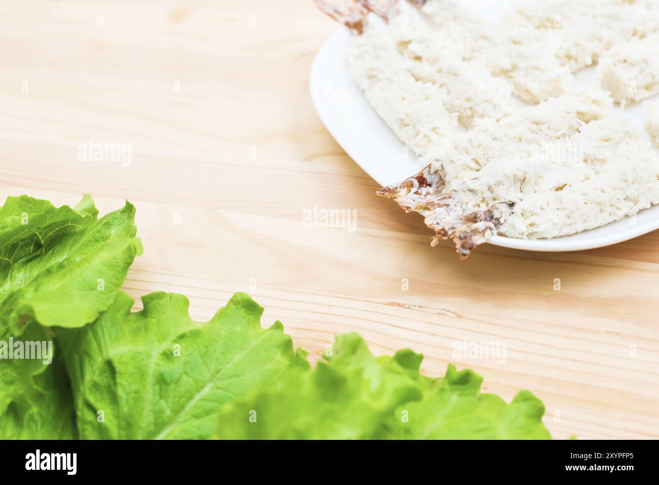 Gamberi crudi in pangrattato vicino a un'insalata di verdure fresche in primo piano su un piatto su un tavolo. Cibo casalingo gustoso e sano Foto Stock
