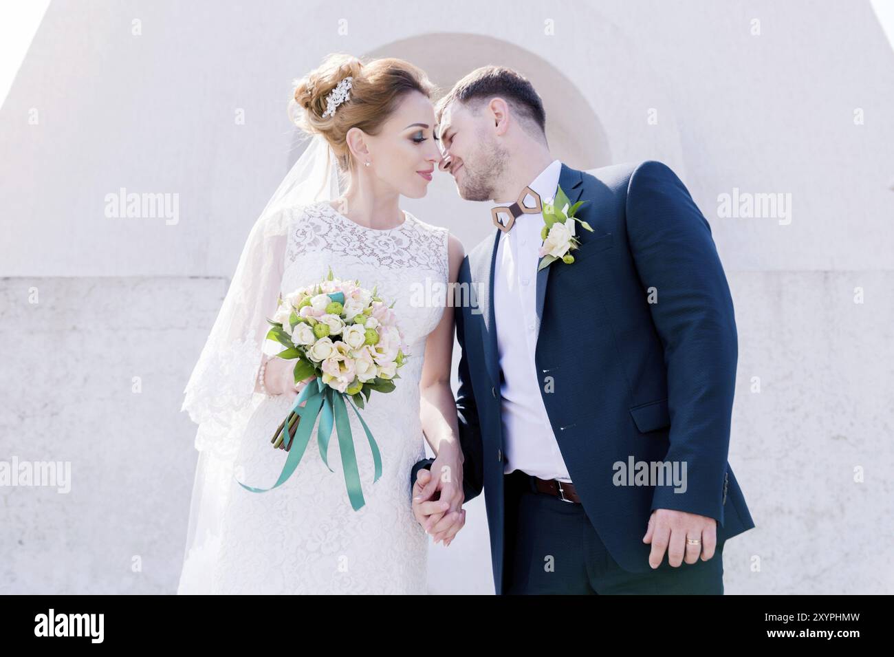 Ritratto di una bella coppia in luna di miele in un giorno di nozze con un bouquet in mano sullo sfondo di un monumento cristiano ortodosso con angeli. Foto Stock