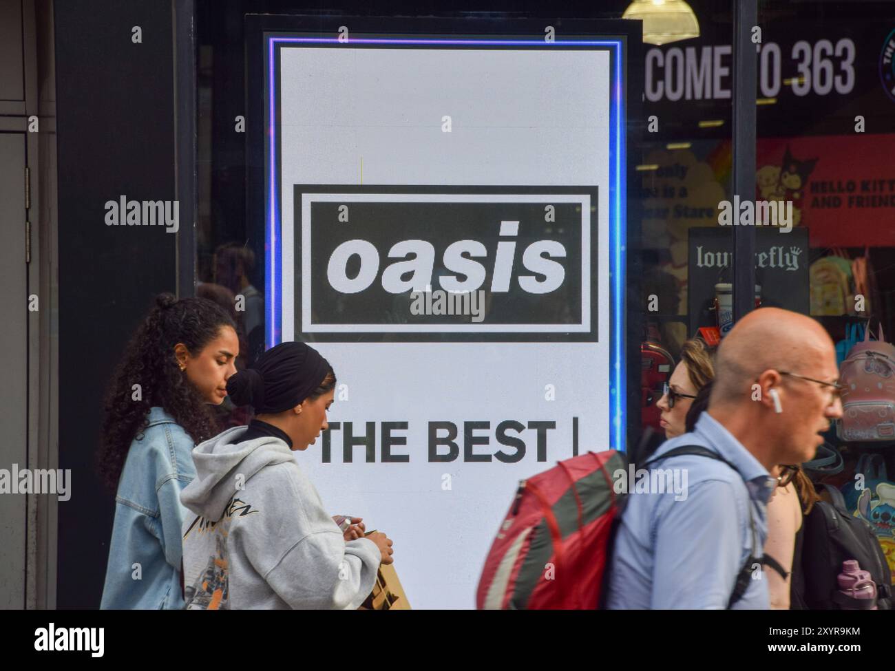 Londra, Regno Unito. 30 agosto 2024. Le persone passano davanti a uno schermo all'HMV Oxford Street promuovendo l'uscita dell'edizione del 30° anniversario di 'Definitely Maybe', l'album di debutto degli Oasis, mentre la rock band di Manchester annuncia altri spettacoli di riunione dopo 15 anni. Crediti: Vuk Valcic/Alamy Live News Foto Stock