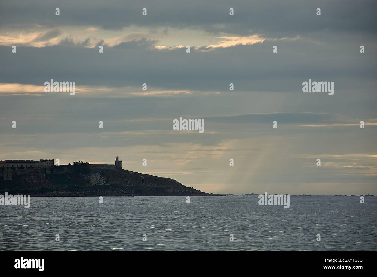 La tranquilla bellezza di Playa America al tramonto, con il Castello di Monte Real sullo sfondo. I raggi d'oro del sole tramonta attraversano t Foto Stock