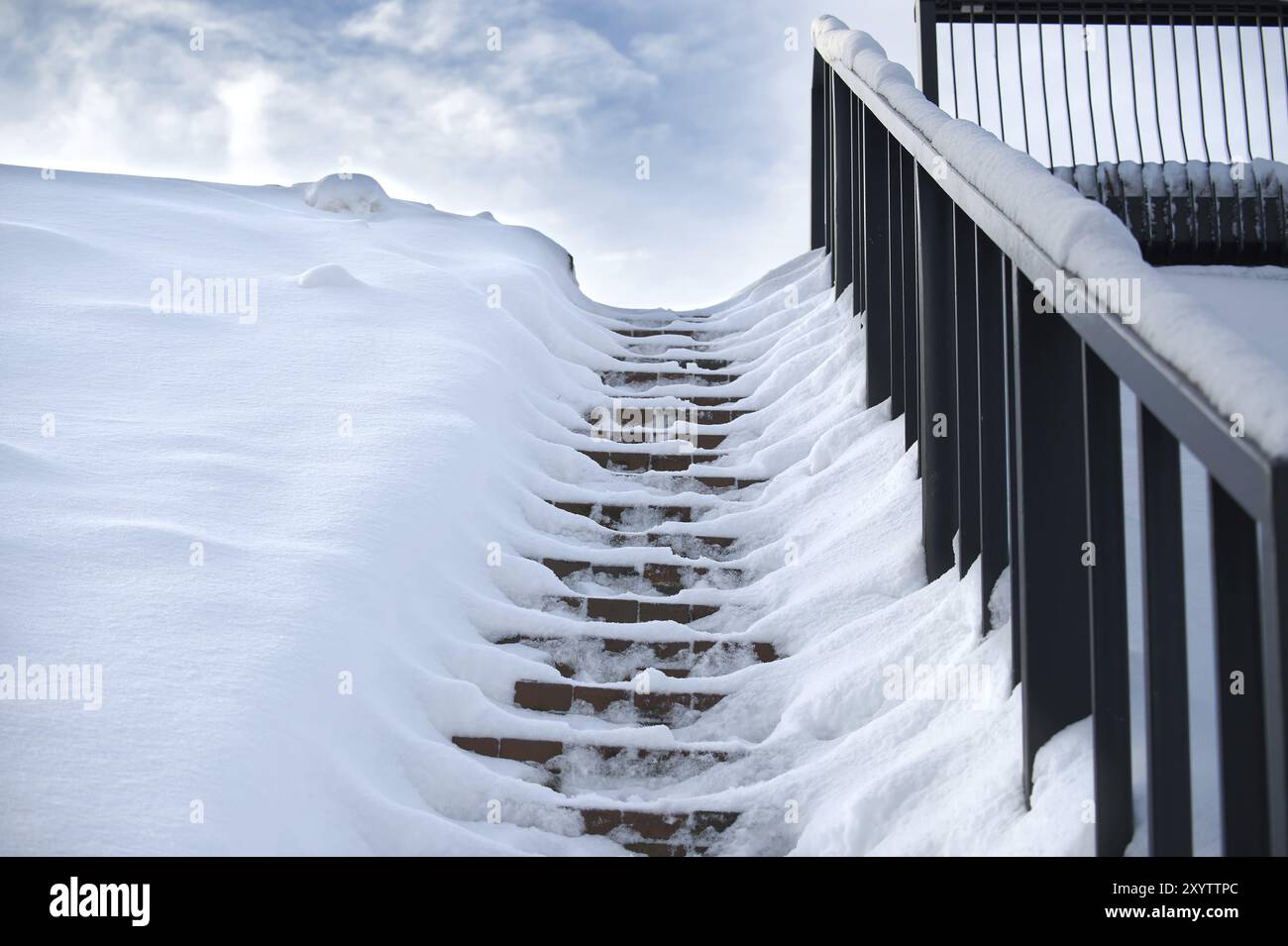 Scena invernale in cui una serie di scale è quasi completamente ricoperta di neve e ringhiere sul lato destro delle scale Foto Stock