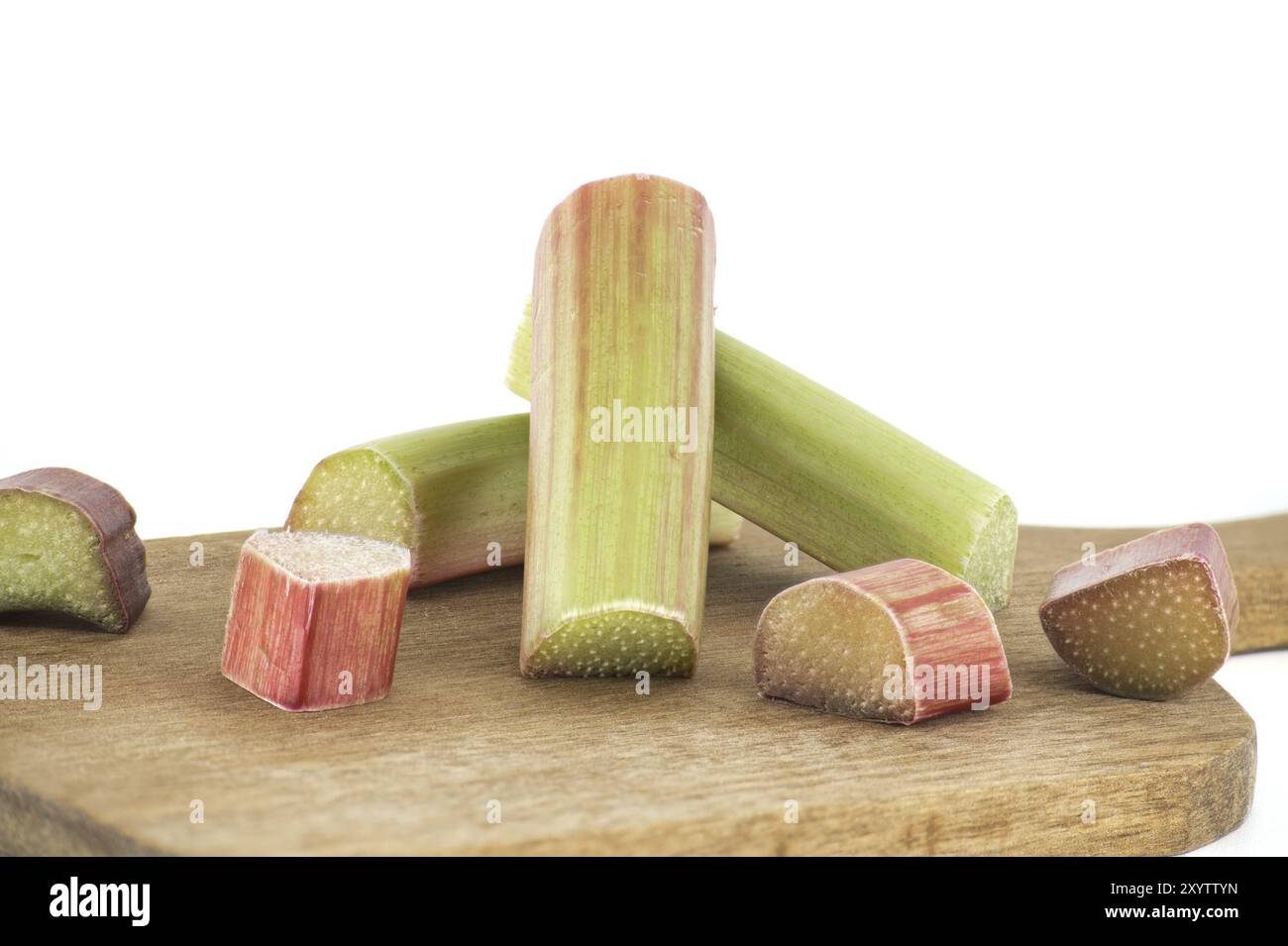 Varietà di gambi di rabarbaro di vari colori, dal verde pallido al rosso intenso su tagliere di legno isolato su sfondo bianco Foto Stock