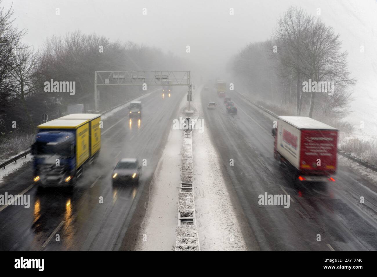 Autocarro e auto in autostrada con neve e scarsa visibilità Foto Stock
