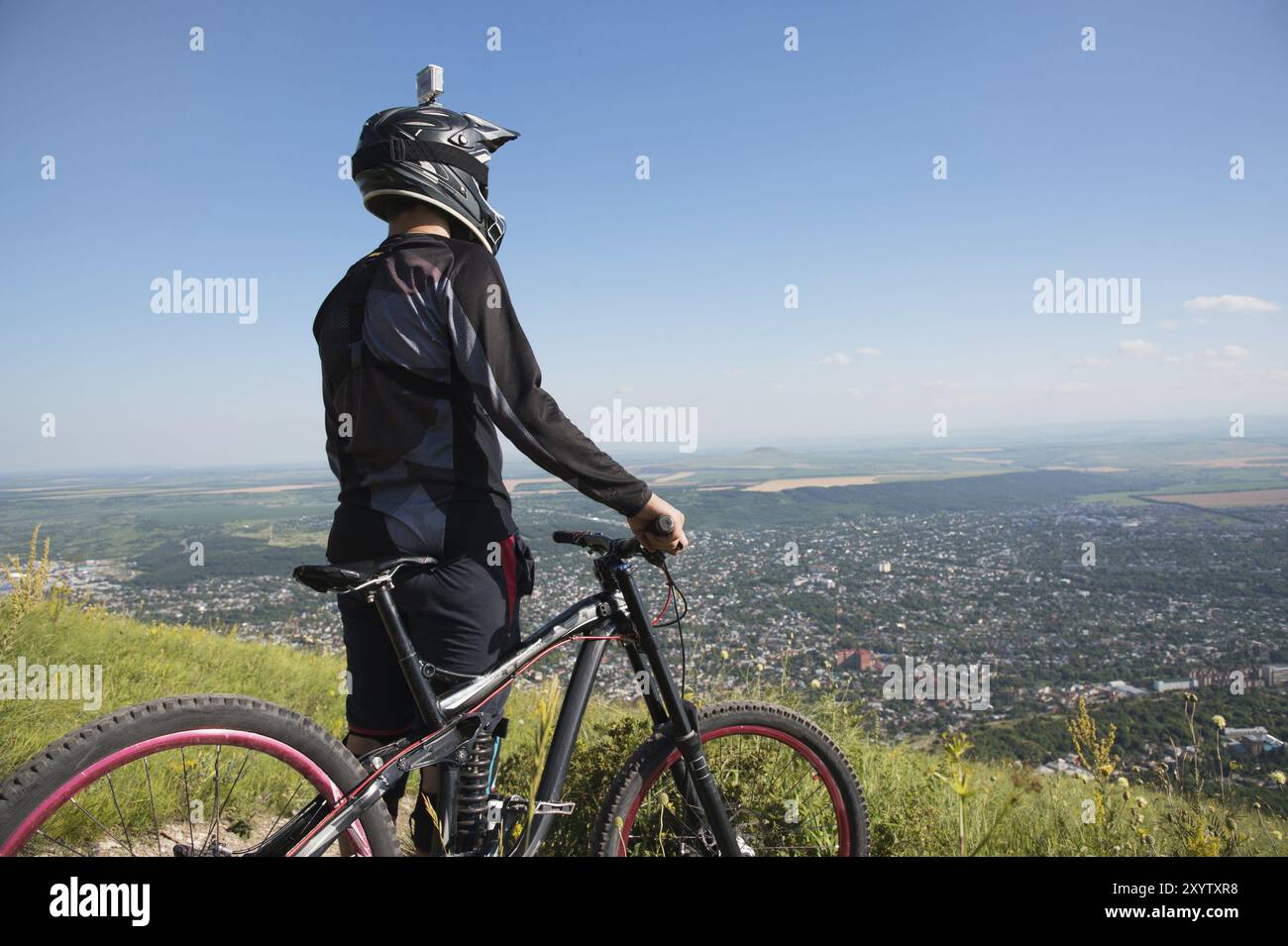 Un giovane ragazzo in piedi sulla tua mountain bike in cima a una montagna, sotto le montagne nuvole basse e nebbia Foto Stock