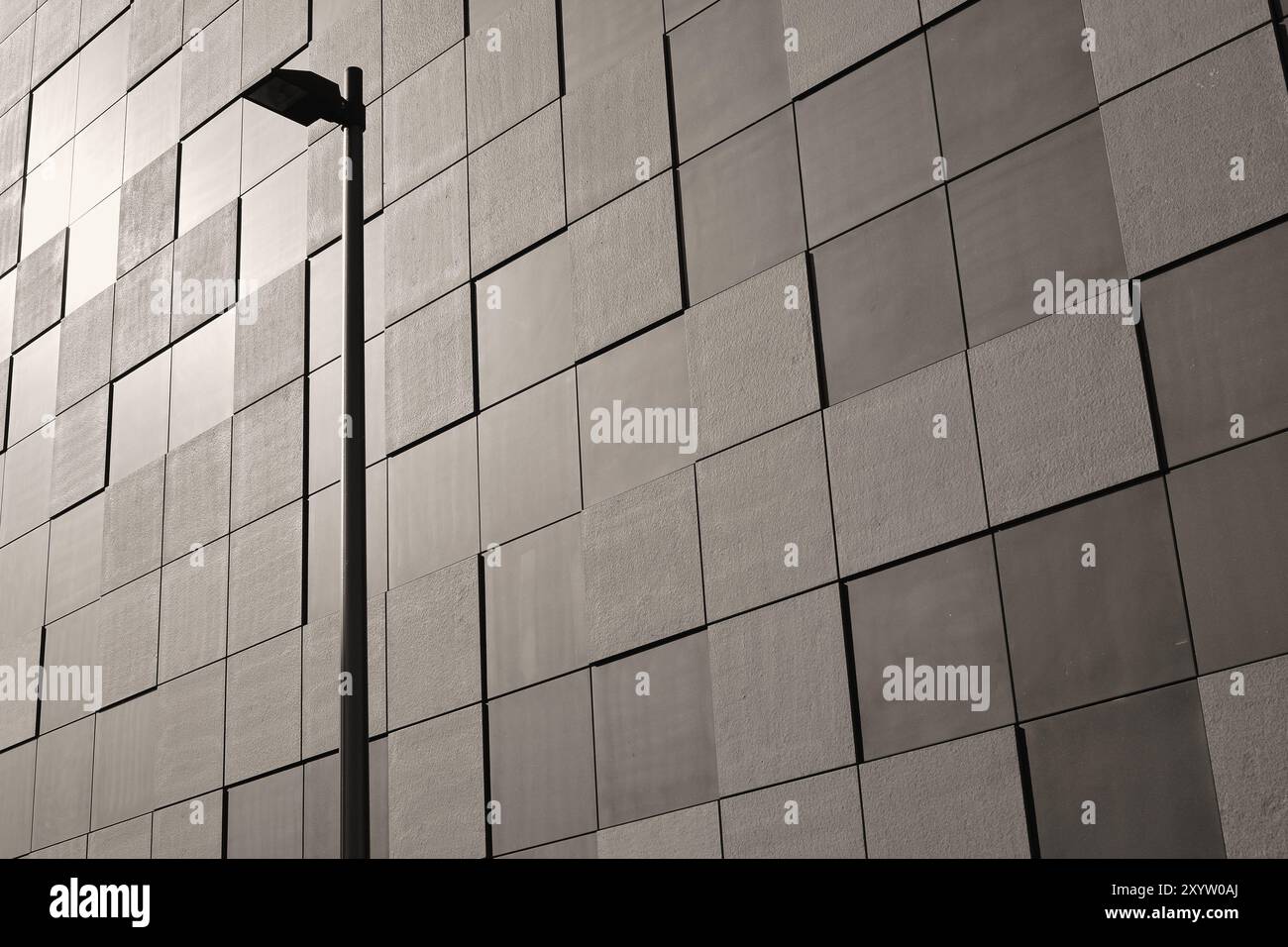 Dettaglio della facciata di un edificio moderno a Magdeburgo. La facciata e' rivestita con lastre di pietra quadrate in uno schema a scacchiera. In primo piano c'è una S. Foto Stock