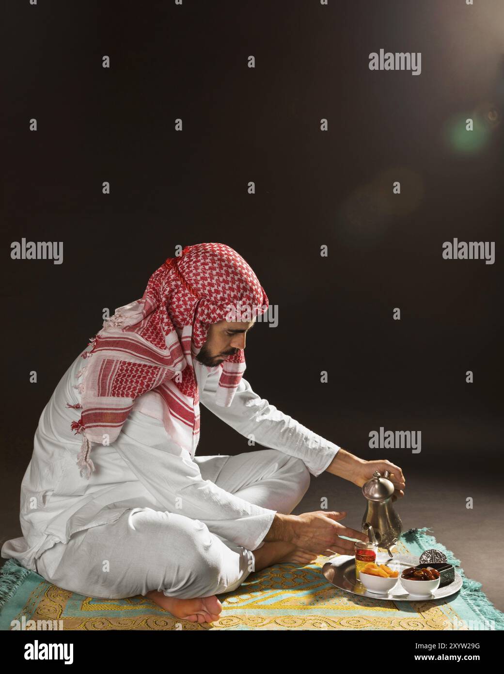 Uomo arabo con kandora che versa il tè Foto Stock