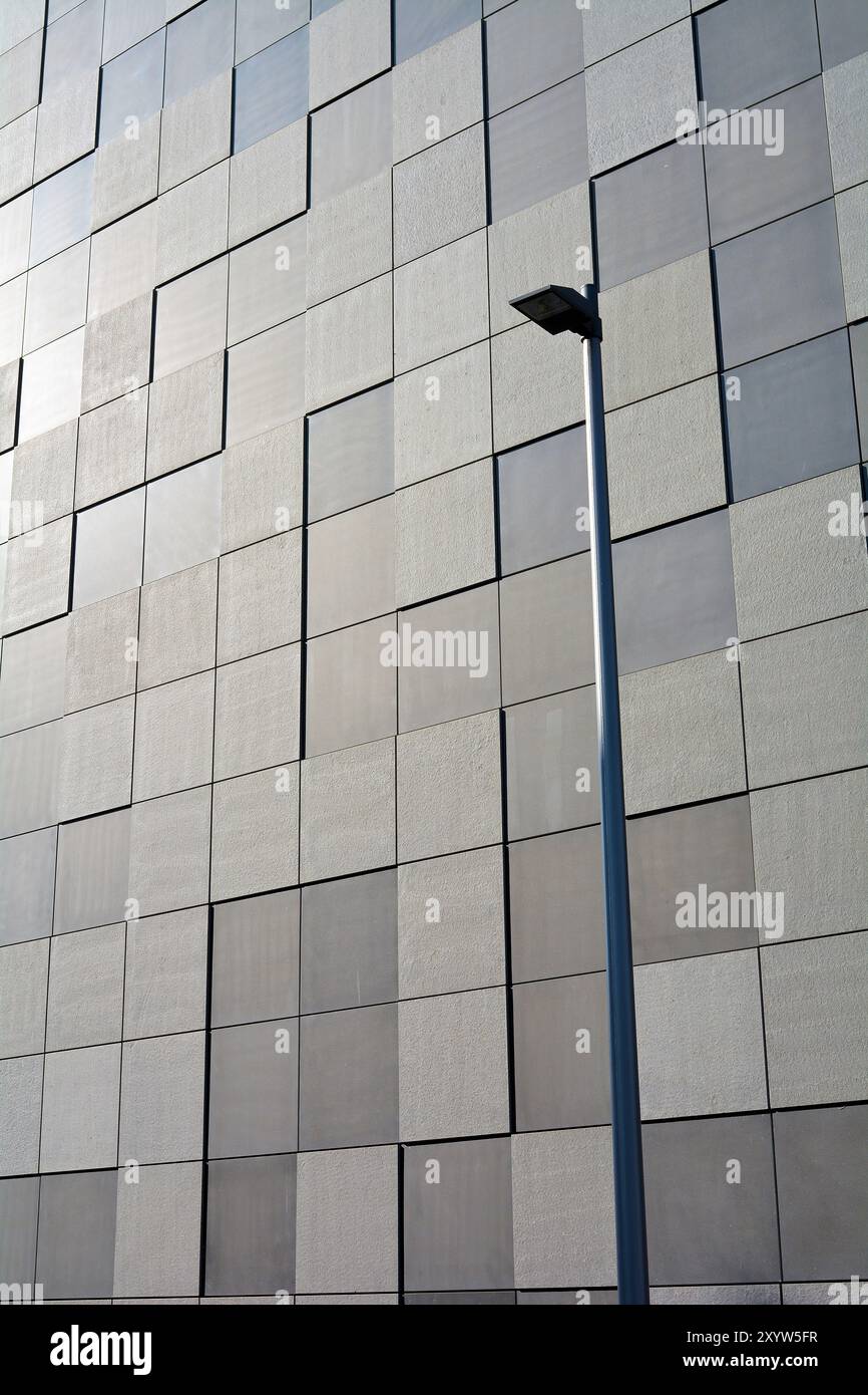 Dettaglio della facciata di un edificio moderno a Magdeburgo. La facciata e' rivestita con lastre di pietra quadrate in uno schema a scacchiera. In primo piano c'è una S. Foto Stock